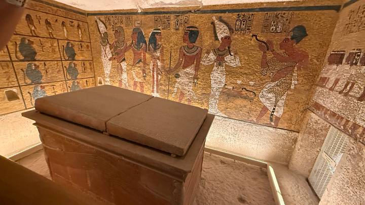 Stone sarcophagus surrounded by colorful wall paintings inside a royal tomb.