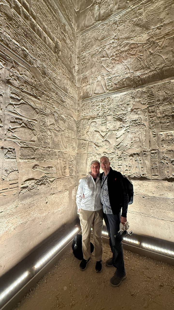 Couple inside a relief-covered chamber illuminated by artificial light.