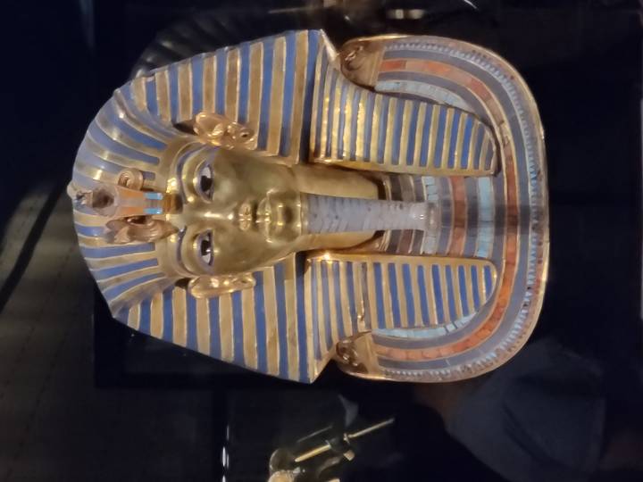 Golden mask of Tutankhamun displayed in glass case.