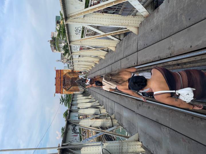 Travelers walk single-file along the narrow rail tracks of Hanoi’s historic Long Biên Bridge.