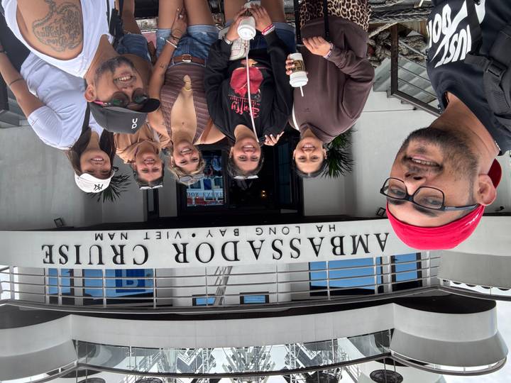 Travelers pose outside the Ambassador Cruise terminal sign before boarding in Ha Long Bay.