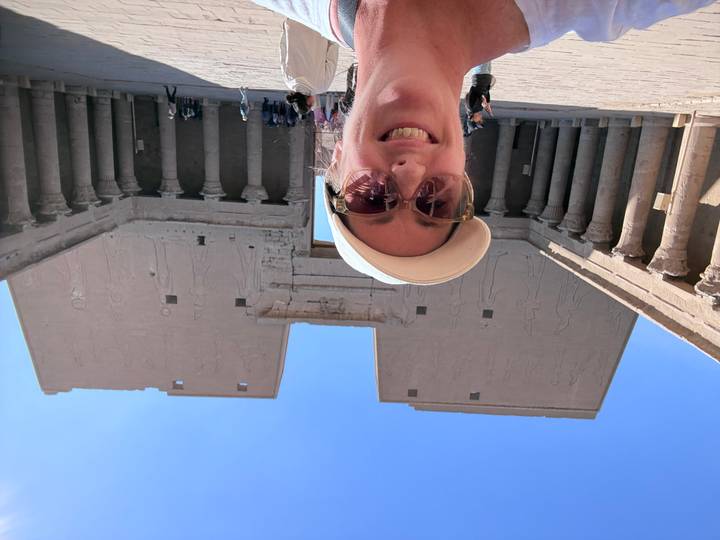 Selfie inside the grand courtyard of Edfu Temple with towering sandstone pylons engraved with deities.