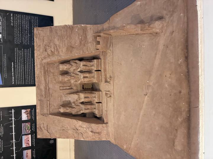 Scale model of Abu Simbel Temple with seated pharaoh statues displayed in a museum.