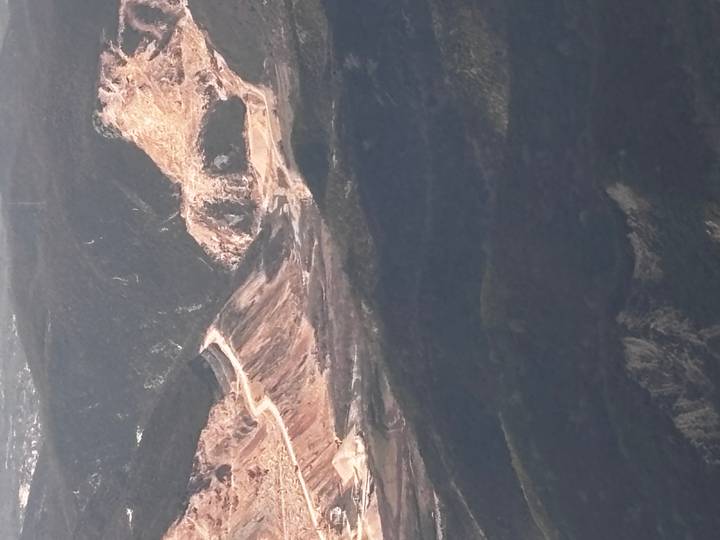 Telephoto shot of a rugged mountain quarry landscape with switchback roads and stripped rock faces.