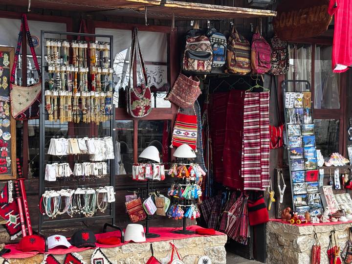 Colorful street stall displaying Albanian handicrafts, textiles, jewelry and souvenirs.