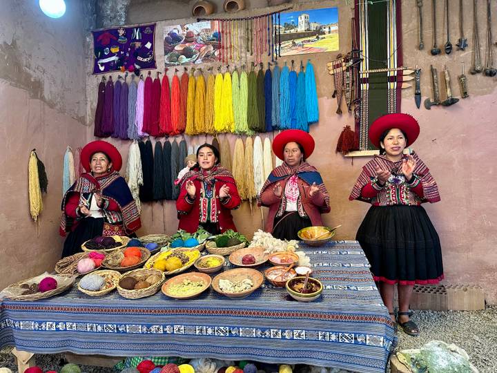 Four Andean women in traditional dress demonstrate natural dyes and colourful wool in the Sacred Valley.