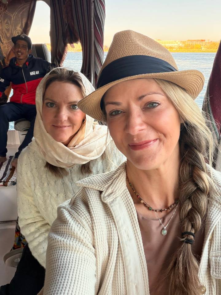Two female travelers smiling for a selfie on a boat interior