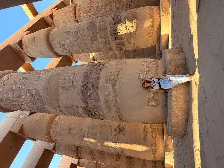 Woman resting against a massive carved column in Karnak Temple
