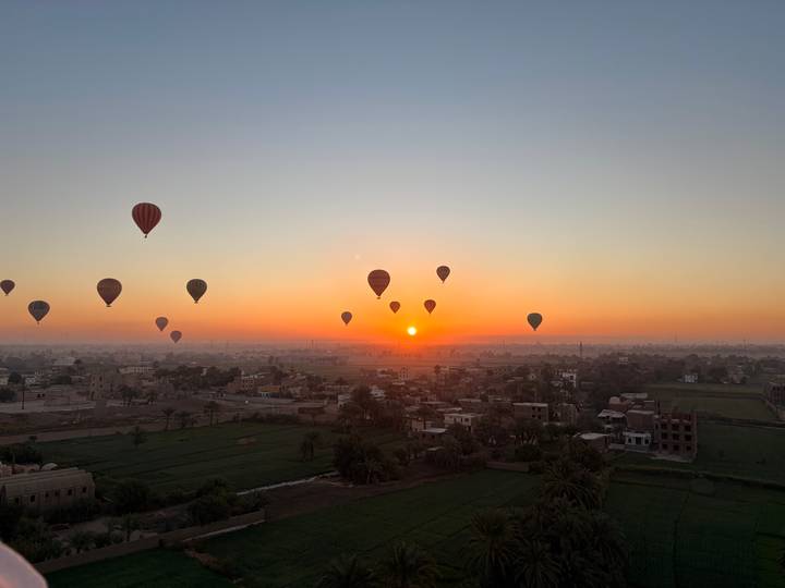 Sunrise panorama with numerous hot air balloons floating above Nile-side farmlands