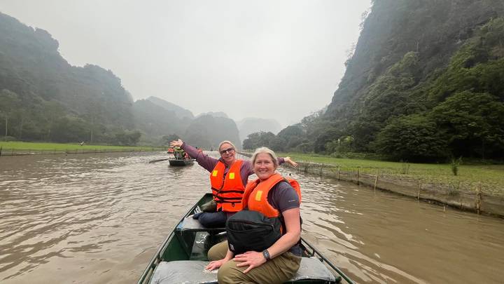 Two travellers in life vests enjoy a misty river valley surrounded by limestone hills.