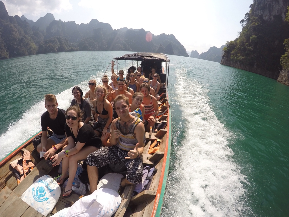 Group of people on a boat in a scenic body of water with limestone cliffs.