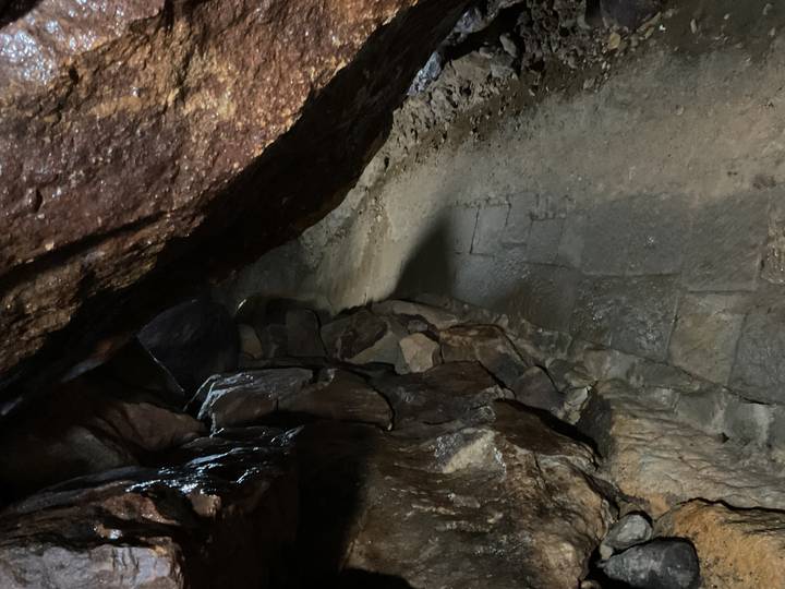 A narrow stone pathway inside a dark, rocky cave passage.