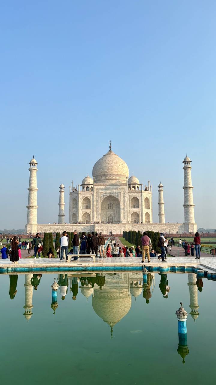 Front view of the Taj Mahal with large crowds in foreground gardens