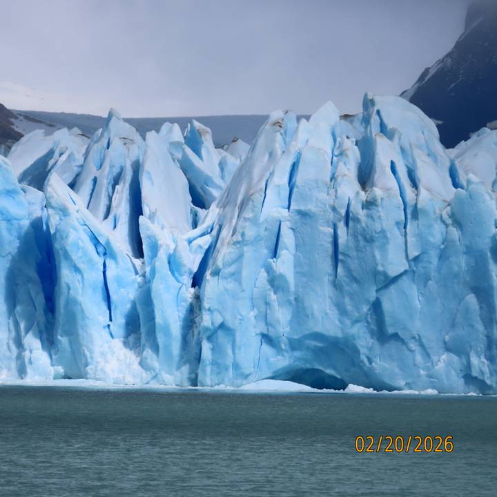 Close-up view of towering blue ice walls of a glacier with deep crevasses.