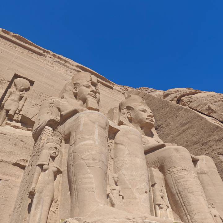 Close detail of the massive statues of Ramses II at Abu Simbel lit by bright sunlight.