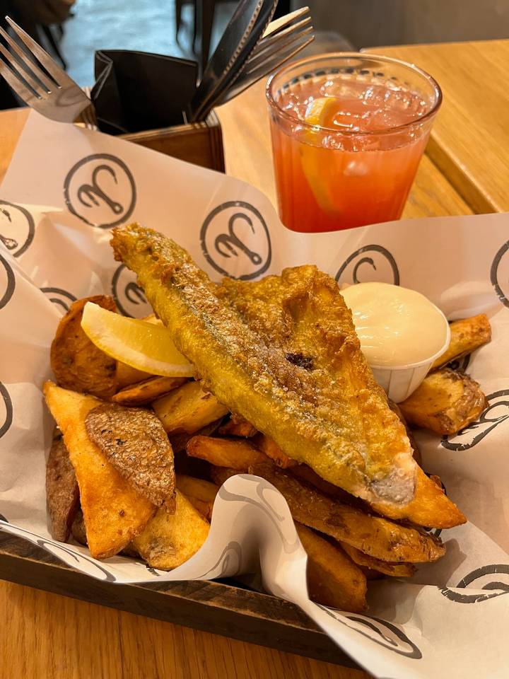 Close-up of golden fried fish and chips served with lemon wedge and aioli.