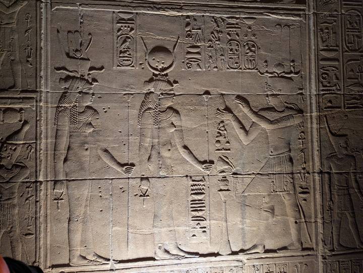 Detailed wall relief depicting ancient Egyptian figures with hieroglyphs, lit by spotlight.