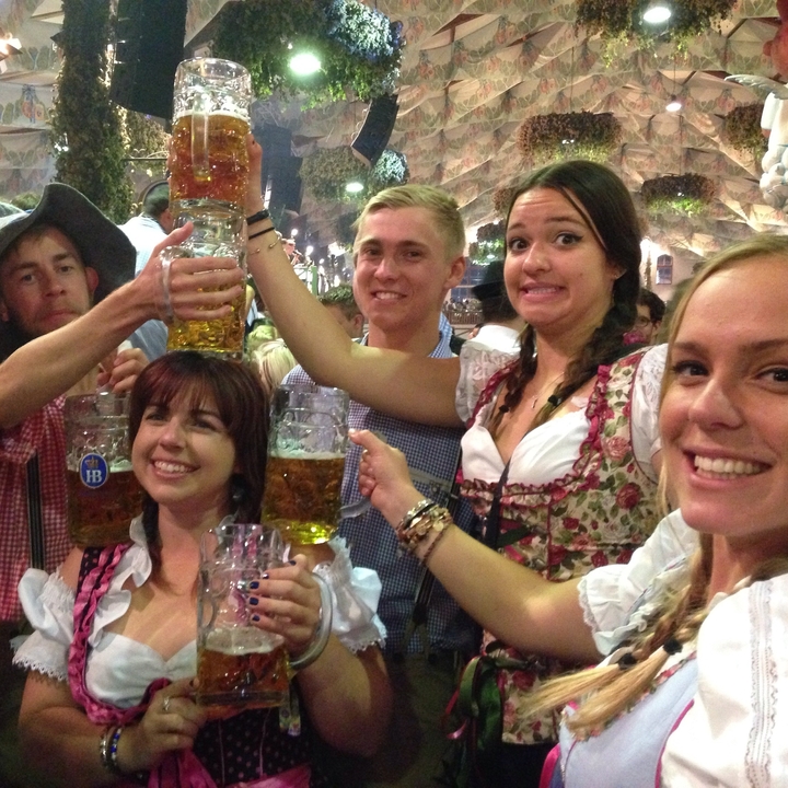 Groupe de personnes célébrant avec des chopes de bière dans un cadre festif.