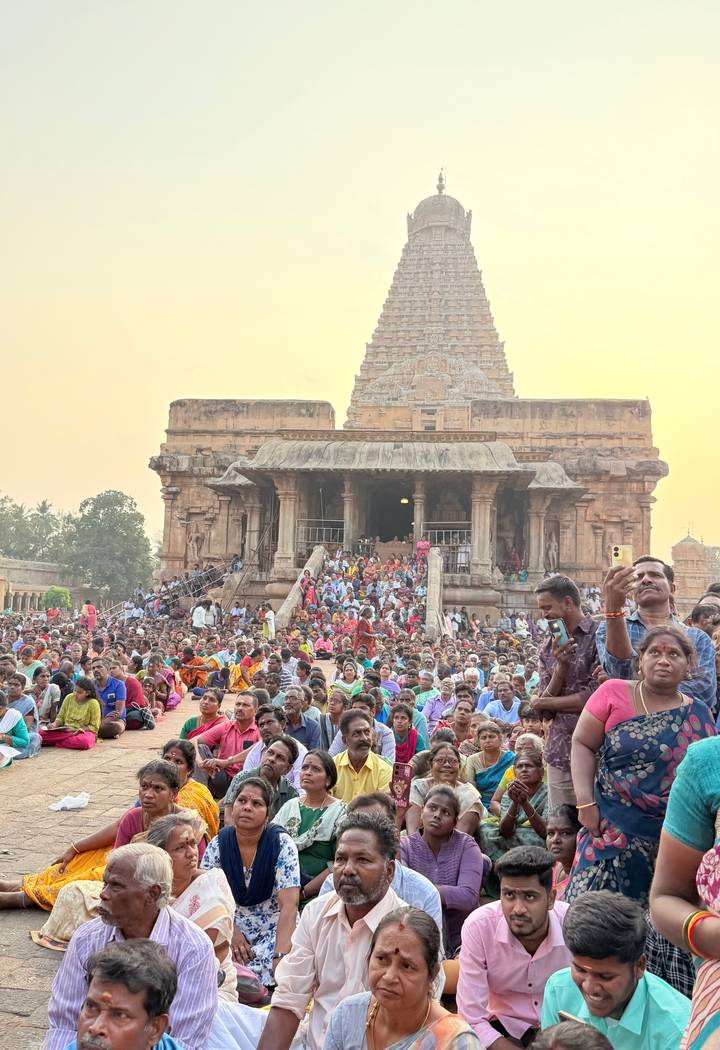 Large crowd gathers on temple steps of Brihadeeswarar Temple at sunset.