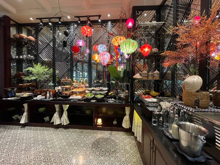 Lavish breakfast buffet with colourful silk lanterns and an array of Vietnamese dishes inside a boutique hotel.