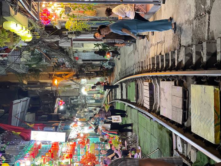 Night view of Hanoi’s famous Train Street with railway tracks running between lively cafés and pedestrians.