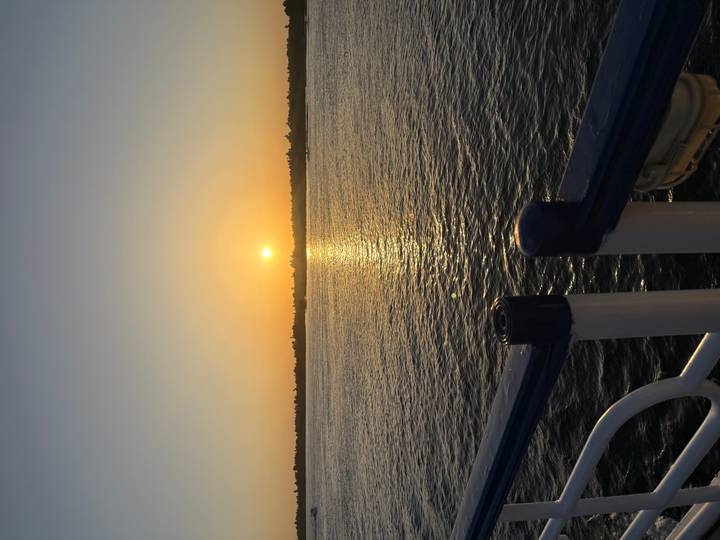 Golden sun setting over a wide calm river with shimmering reflection on the water surface