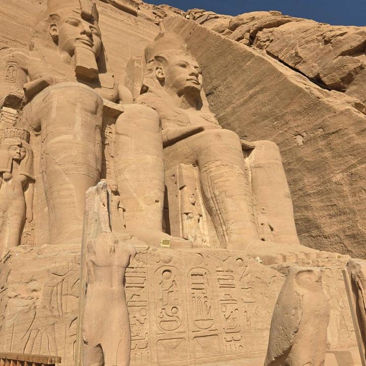 Close-up of colossal seated statues carved into the sandstone facade of Abu Simbel temple