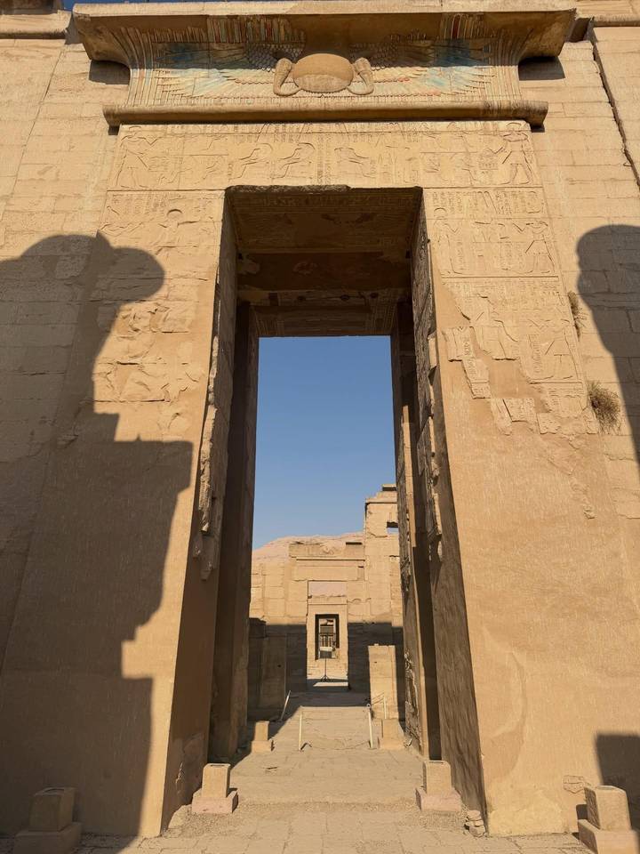 Stone doorway and hieroglyph-covered pillars framing a view of desert mountains beyond