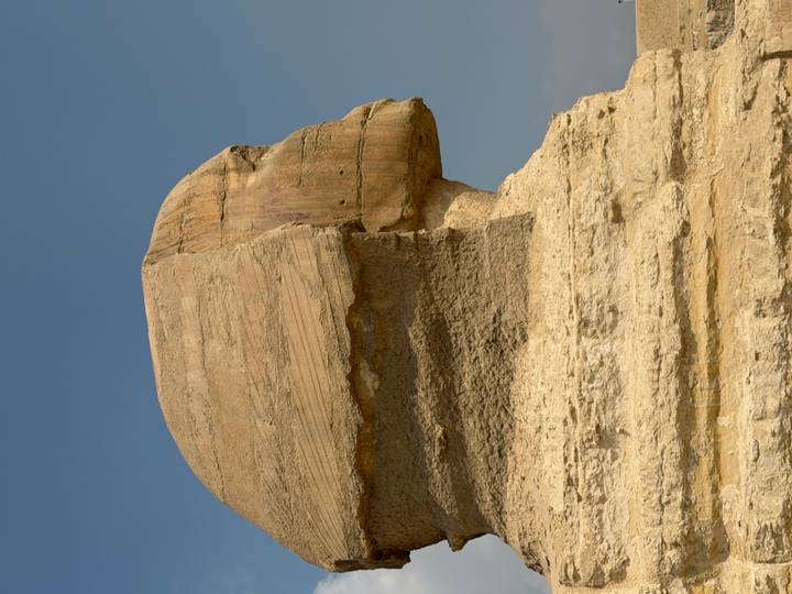 Profile view of the Great Sphinx statue carved from limestone under clear sky.