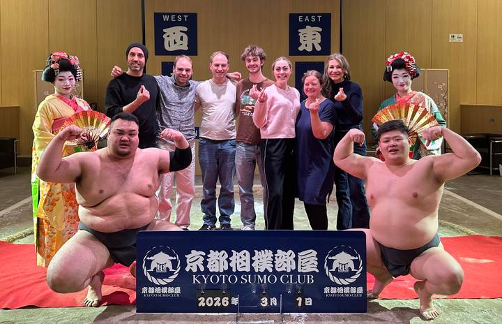Group photo with sumo wrestlers and geisha performers inside the Kyoto Sumo Club arena.