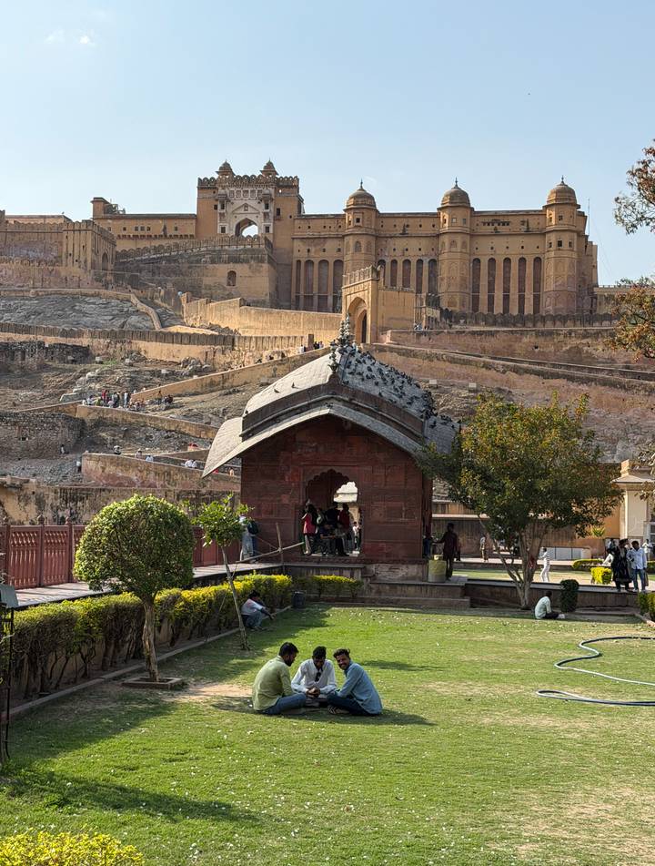 Visitors explore Amber Fort’s sandstone ramparts and courtyards in Jaipur with manicured shrubs in foreground.
