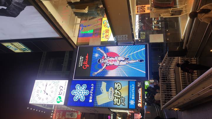 Night scene of Osaka’s famous Glico running man neon sign amid bright city lights.