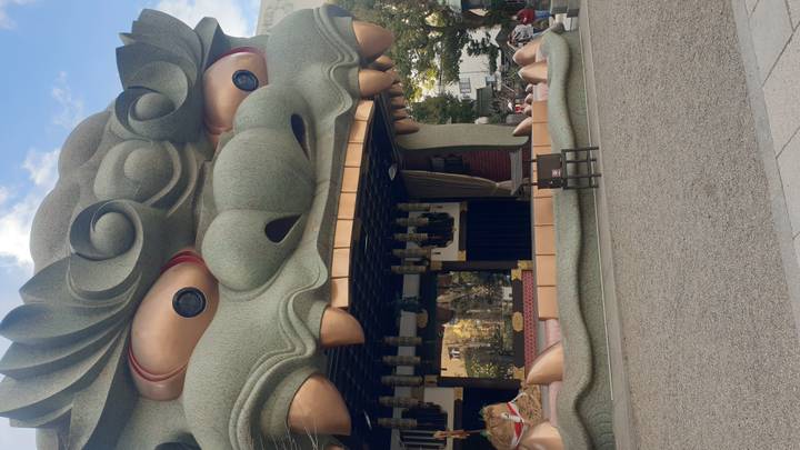 Large lion-head stage structure at Namba Yasaka Shrine in Osaka under a partly cloudy sky.
