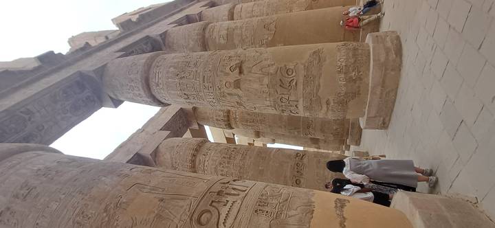 Massive hieroglyph-covered columns of Karnak Temple towering above visitors in the hypostyle hall.