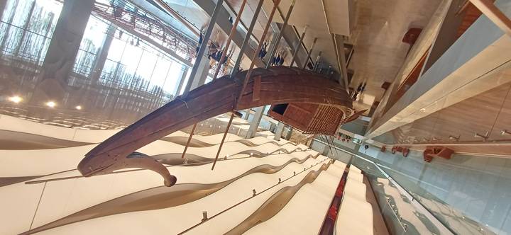 Ancient wooden solar boat displayed inside the modern Grand Egyptian Museum gallery