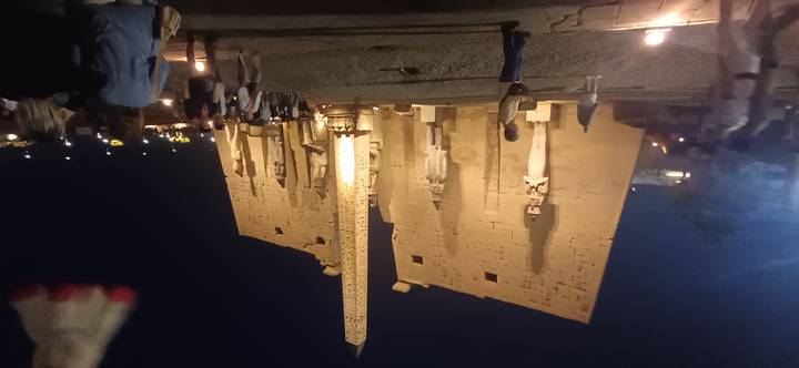 Night view of Luxor Temple entrance illuminated with an obelisk and colossal statues