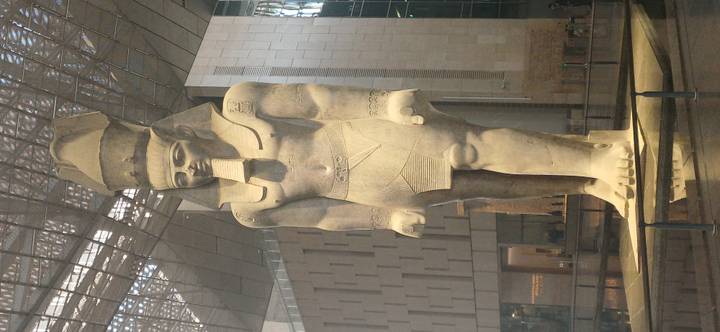 Massive standing statue of Ramses II inside a high-ceilinged museum atrium