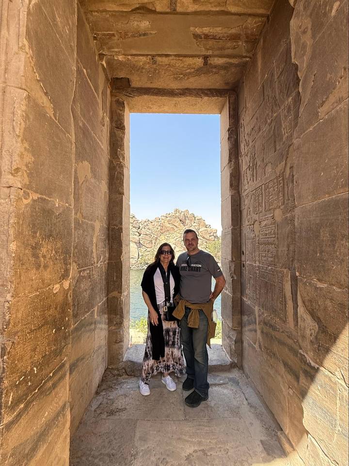 Couple framed by stone gateway with hieroglyphs overlooking Lake Nasser at Philae Temple.