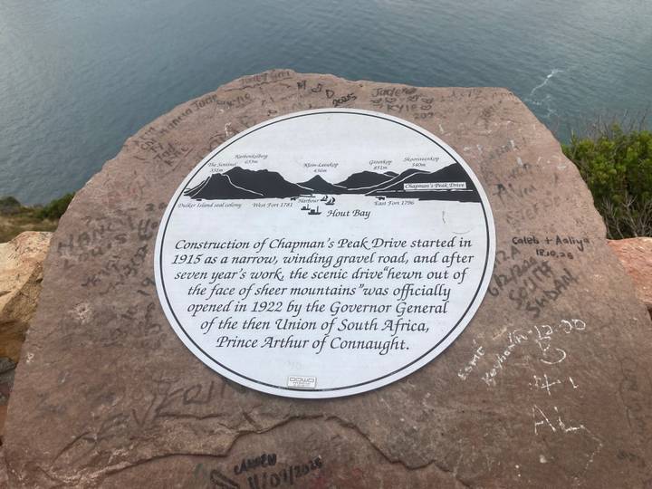 Historical information plaque about Chapman’s Peak Drive mounted on a rock overlooking the sea.