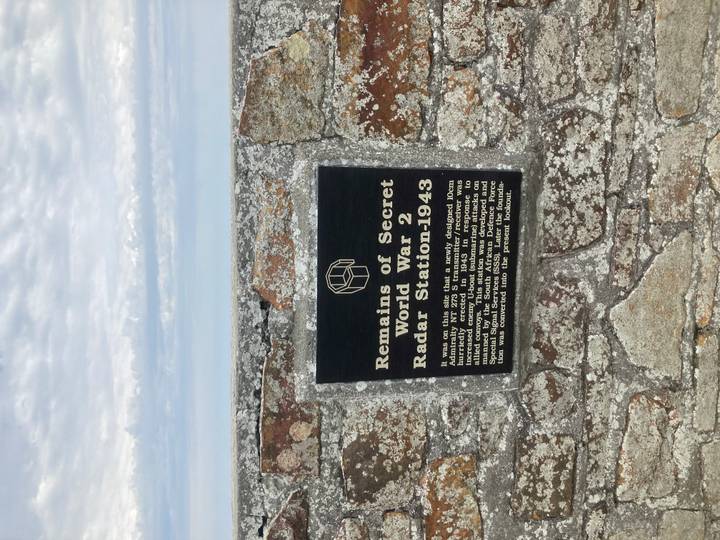 Black plaque on a stone wall describing a World War II radar station site.