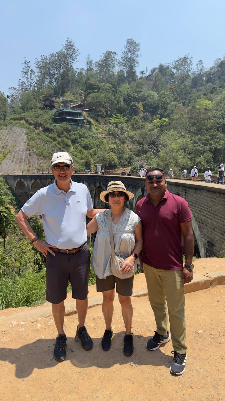 Travellers pose with their guide by the famous Nine-Arch Bridge surrounded by lush greenery.