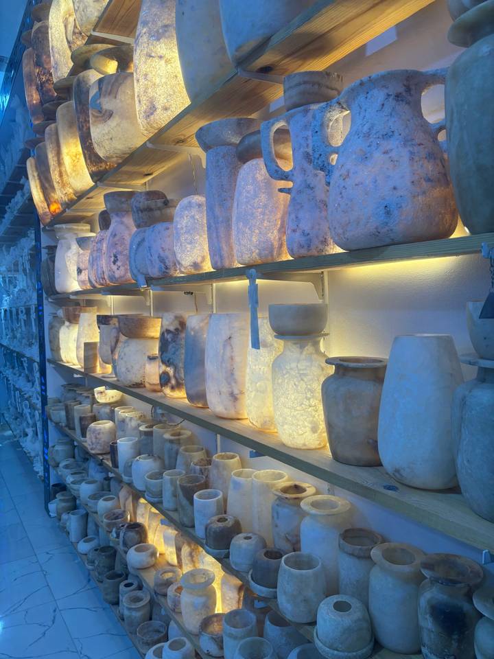 Back-lit shelves displaying alabaster vases and candle holders in a souvenir shop