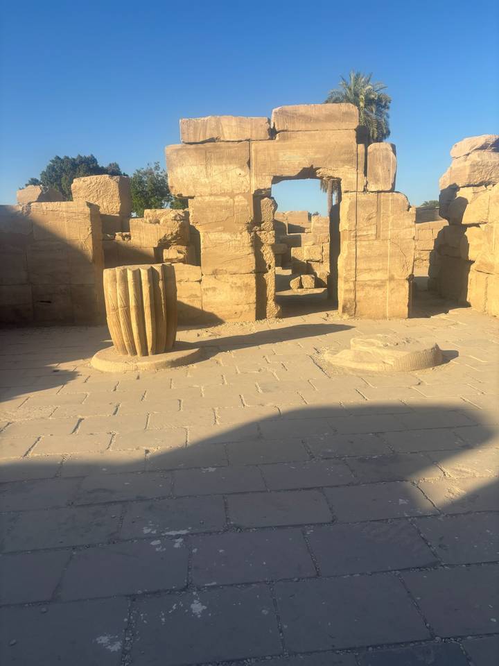 Sunlit ancient stone floor with broken column base ruins inside Karnak Temple complex