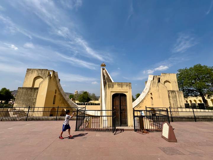 Young boy observing a massive yellow stone sundial at Jaipur's Jantar Mantar