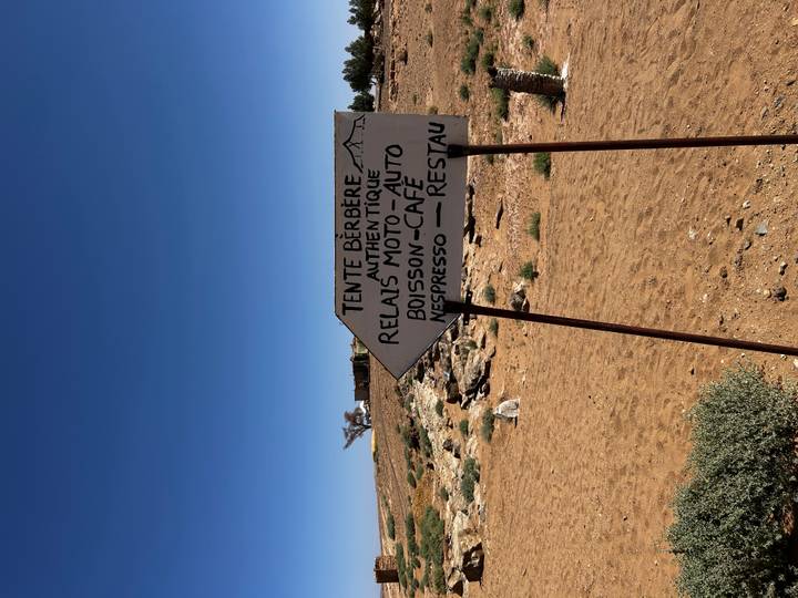 Hand-painted roadside sign points the way to a Berber tent café in the desert.