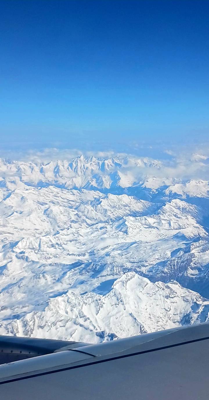 Aerial view of vast snow-covered mountain range seen from an airplane window.