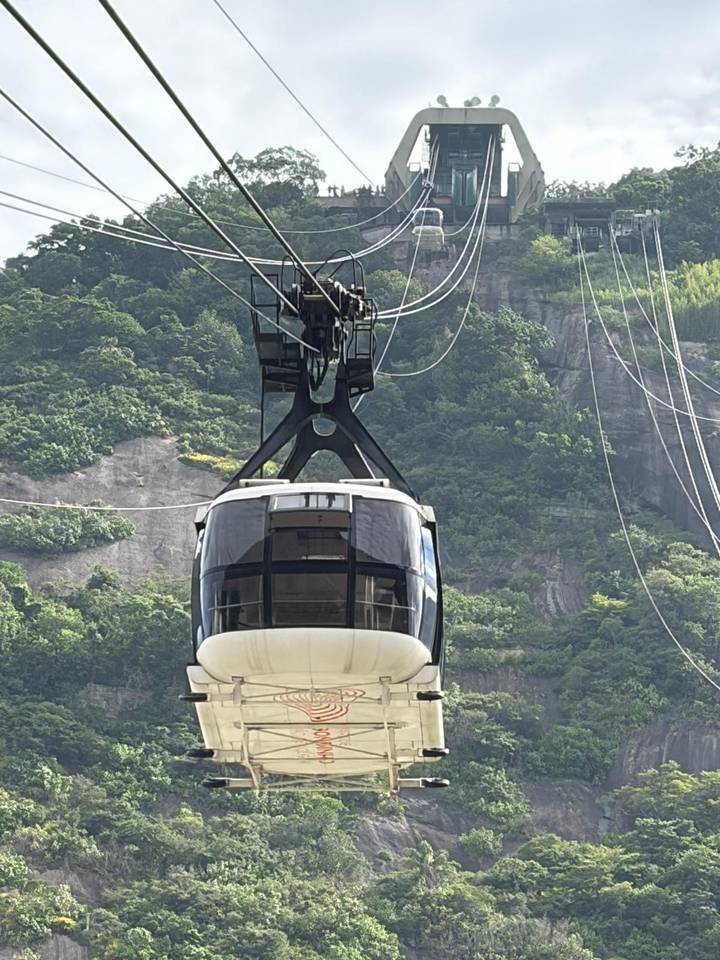 Sugarloaf cable car ascending against a backdrop of green cliffs and hanging cables.