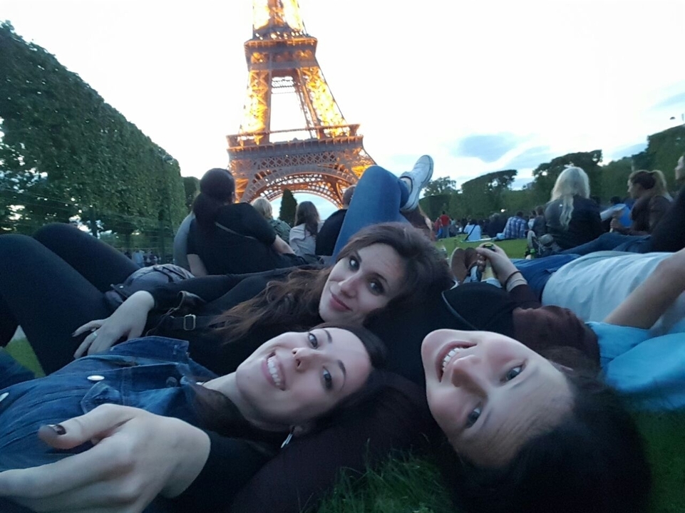 Des gens se détendent sur l'herbe avec la Tour Eiffel en arrière-plan.