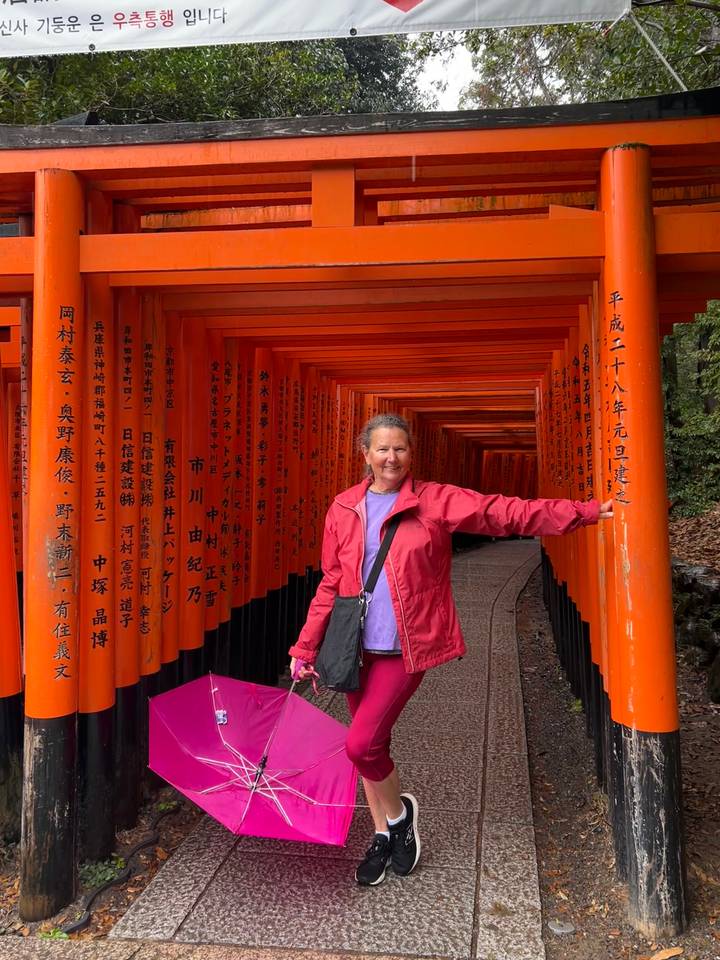 Traveler stands among endless vermilion torii gates at Fushimi Inari shrine.