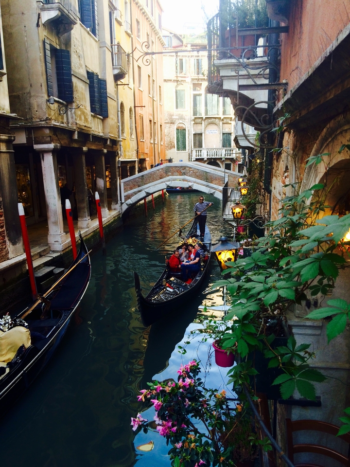 Gondole naviguant sur un canal avec des ponts et des bâtiments historiques à Venise.
